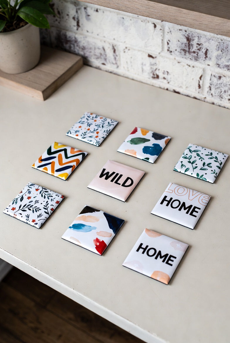 A pack of 9 square custom photo magnets with various designs on a light surface.