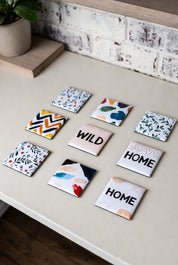 A pack of 9 square custom photo magnets with various designs on a light surface.