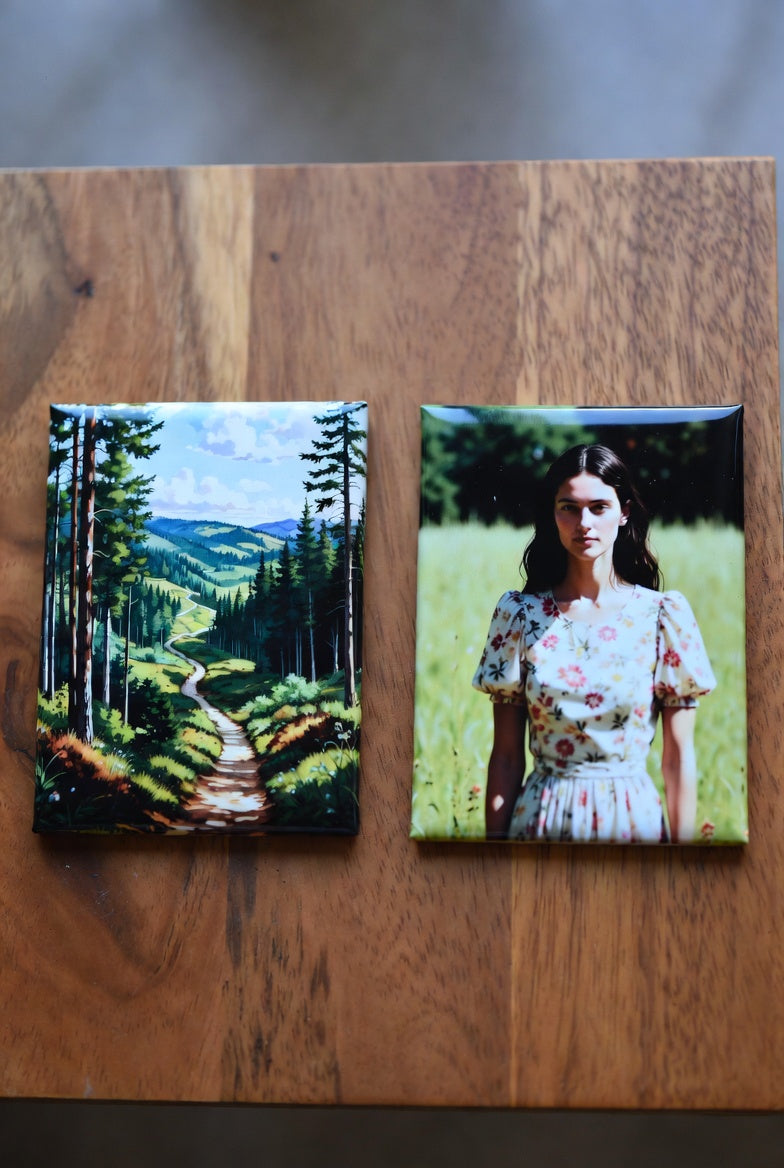 Two rectangle magnets on a wooden surface, one depicting a forest and the other a person in a field.