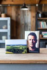 Two custom rectangle photo magnets on a wooden surface with a blurred background of a room.